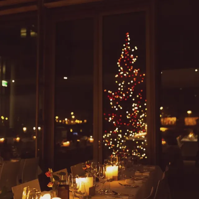 Festliche Tafel mit Kerzen vor einem leuchtenden Weihnachtsbaum